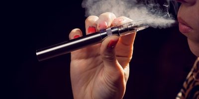 Image of young woman in profile smoking an e-cigarette