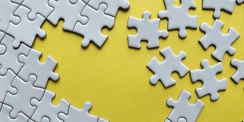 JIgsaw puzzle pieces being put together on a yellow background