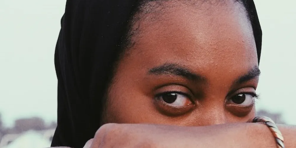 Woman in black hijab covering her face with her hand